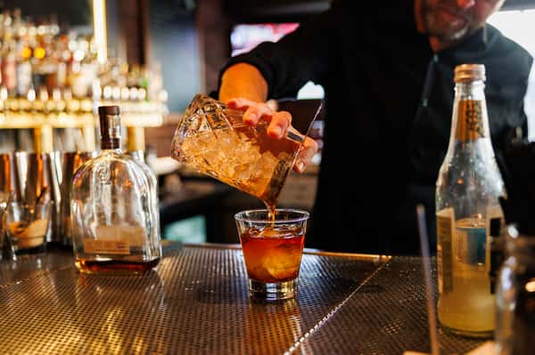 Bartender pouring a handcrafted cocktail over ice at EVO Old Town Scottsdale, highlighting the restaurant's elevated craft beverage program.