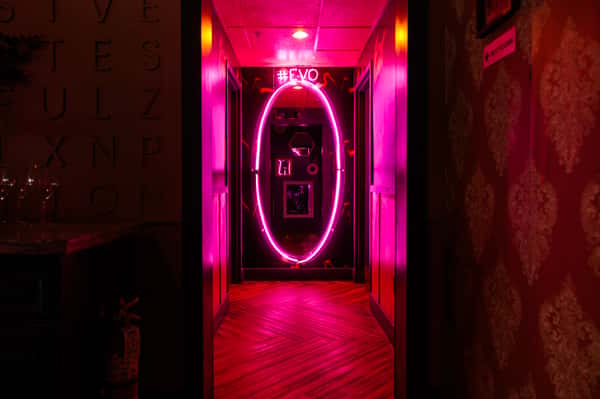 Vibrant neon-lit entrance hallway at EVO North Scottsdale featuring bold pink lighting and a trendy nightlife ambiance.