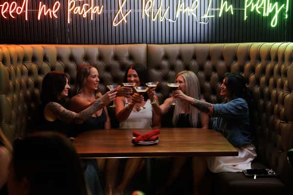 Friends toasting cocktails in a stylish booth at EVO Old Town Scottsdale, creating a lively social dining and nightlife experience.