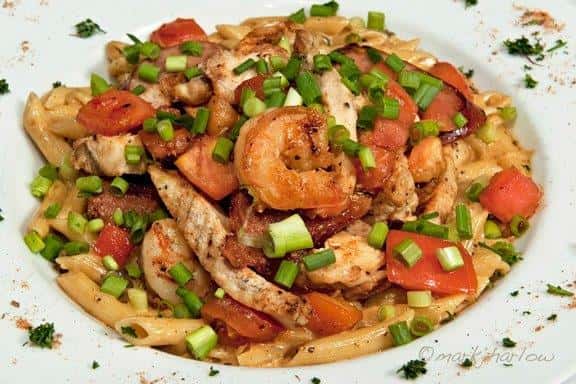 Penne Jambalaya. Broiled chicken breast, shrimp and smoked sausage sauteed with mushrooms, green onions, and tomatoes. Tossed with penne noodles in a Cajun cream sauce