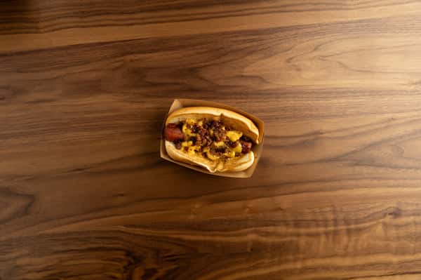 Crafty Dog hotdog featuring beer cheese sauce, bacon bits, and fried jalapeños served on a soft bun.