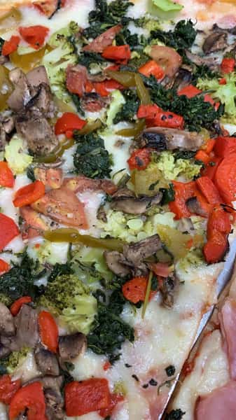 Vegetarian gourmet pizza with melted cheese, broccoli, spinach, peppers, tomato, mushroom, and garlic