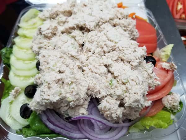 A salad with romaine lettuce, cucumbers, tomatoes, olives, red onion, topped with tuna salad