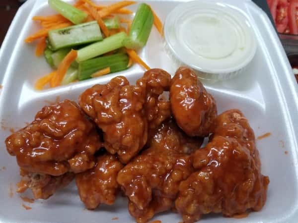 boneless chicken wings covered in sauce with a side of celery and shredded carrots