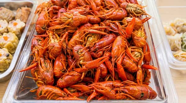 A pile of bright red cooked crawfish in a clear serving container.
