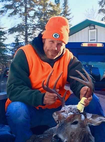 man posing for a photo with a deer