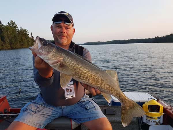 man holding a fish posing for a photo