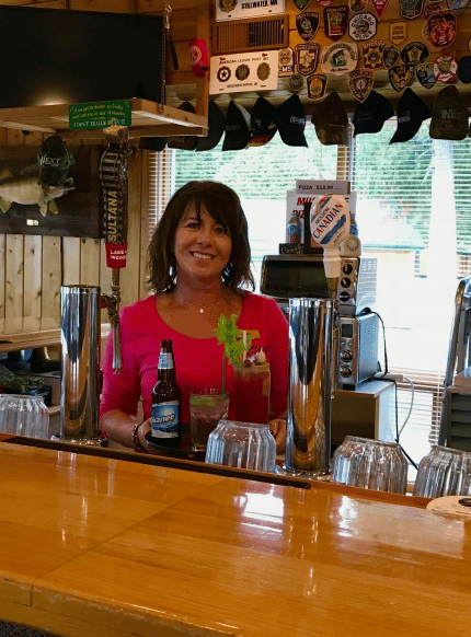 woman standing behind the bar smiling for a photo