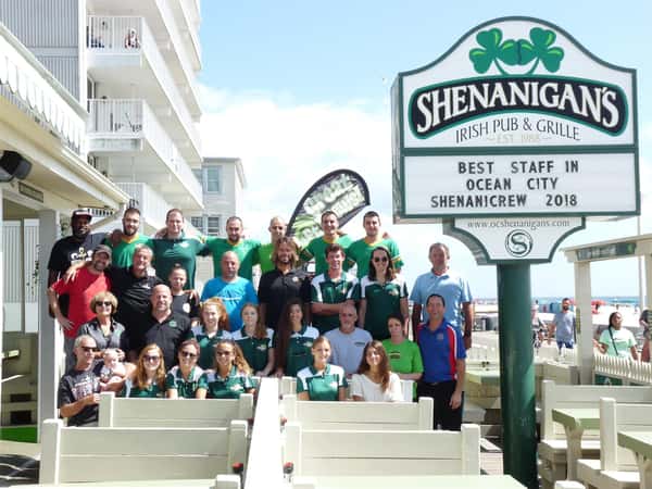 Staff of Shenanigans group photo outside on the boardwalk by the Shenanigan's sign.