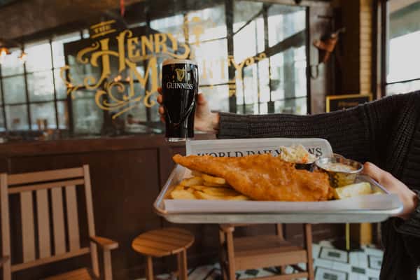 Classic fish and chips served with tartar sauce and a pint of Guinness, presented inside an Irish pub dining room