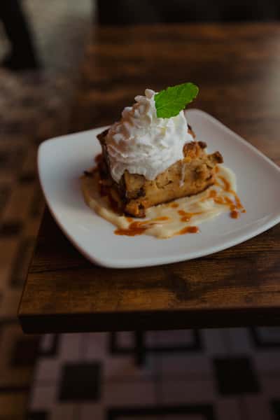 Warm dessert square topped with whipped cream and caramel drizzle, garnished with mint and served on a white plate at an Irish pub