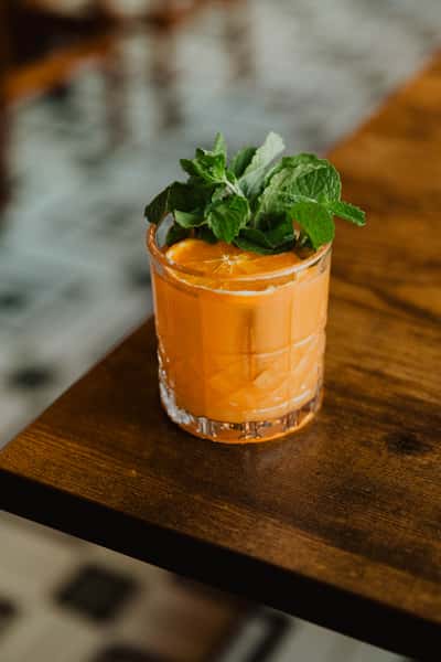 Bright orange cocktail garnished with fresh mint leaves, served in a lowball glass at an Irish pub bar.