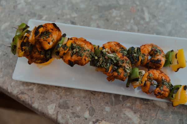 Grilled chicken skewers with bell peppers and herbs, served on a rectangular plate, showcasing bold pub flavors and flame-grilled preparation.