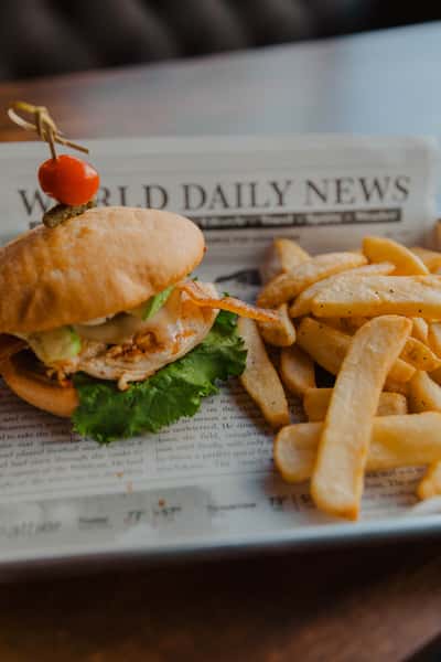Crispy chicken sandwich with lettuce and sauce, served with thick-cut fries on a newspaper-lined tray at an Irish pub