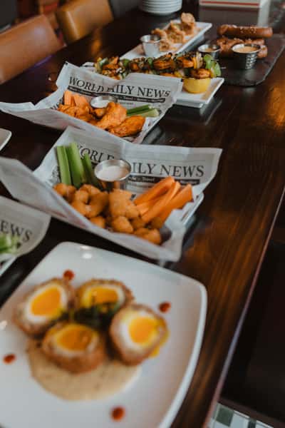 Assorted Irish pub appetizers including chicken wings, fried bites, celery and carrot sticks, and dipping sauces, served family-style on a wooden table.