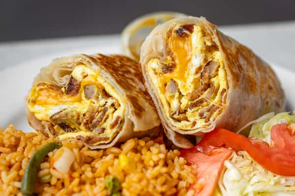 Breakfast burrito with eggs, cheese, and sausage served with seasoned rice, lettuce, and tomato on a plate.