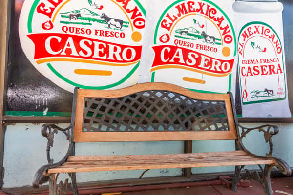 wooden bench under Queso Fresco Casero sign