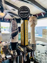 Craft beer tap handles at The Riders Club Cafe, featuring Dust Bowl Brewing's Sunbather Blonde Ale and other rotating draft selections, set against a bright and airy bar interior.