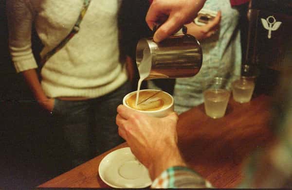 barista pouring milk into coffee