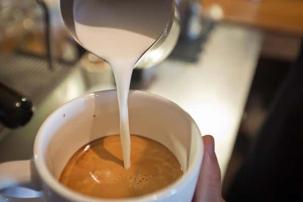 milk pouring into coffee cup