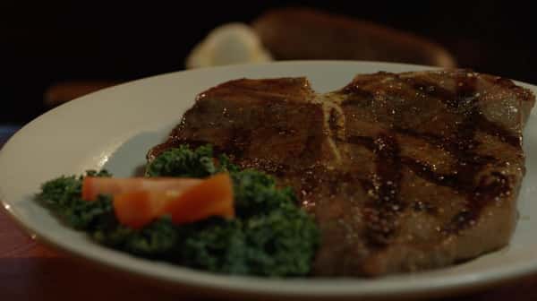 t bone on a plate with an orange garnish