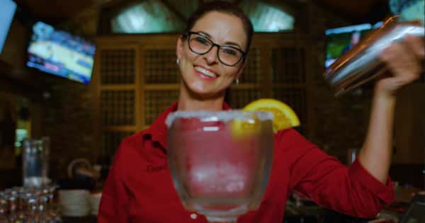 waitress smiling while handing over a margarita