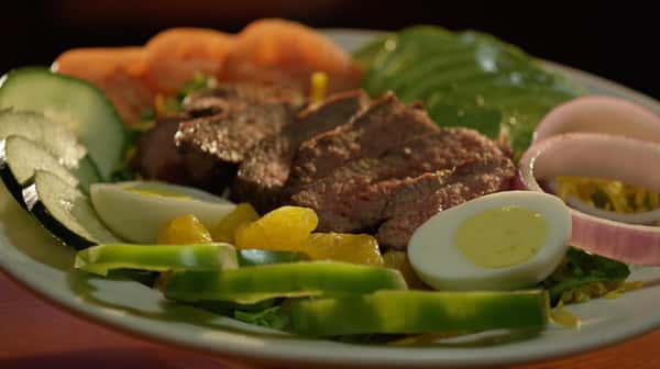 steak salad on a plate with peppers, cucumbers, onions and hard boiled eggs