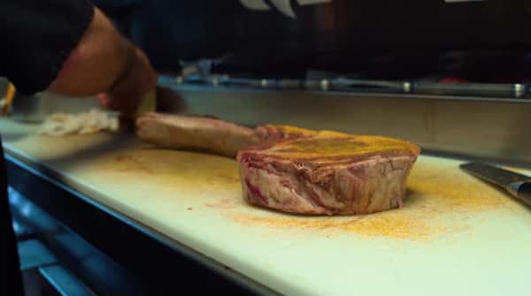meat being seasoned in the kitchen by the chef