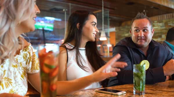 woman at the bar with a drink in front of her next to a man
