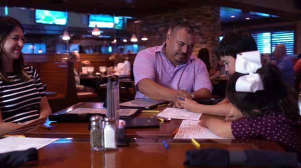 Family at a dining table with a kid coloring