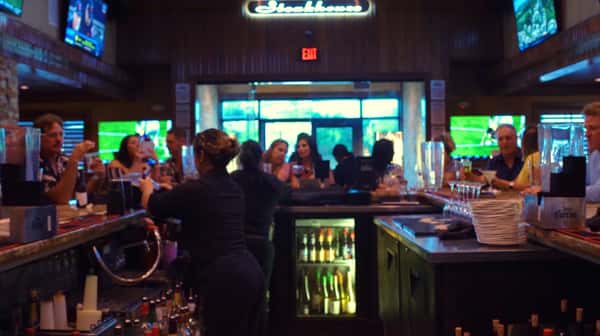crowded bar filled with patrons and bartenders filling glasses