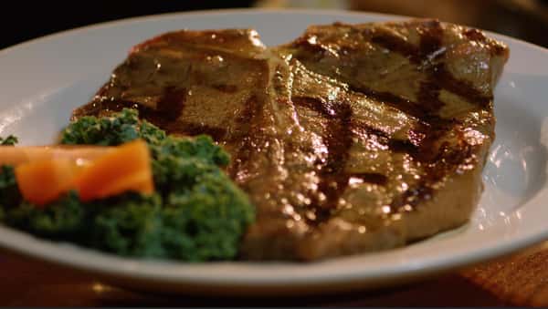 t bone on a plate with an orange garnish