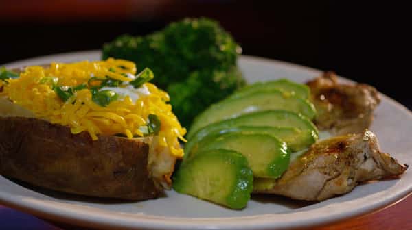 chicken with avocado and a baked potato with a side of broccoli