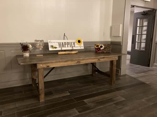 Rustic wooden gift table decorated with flowers, a sunflower basket, and a "Happily Ever After" sign, designated for cards and gifts.