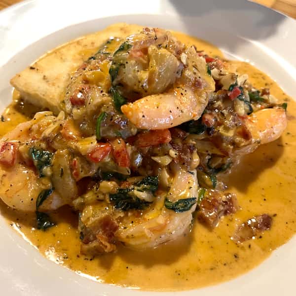 Shrimp . Spinach . Fried Garlic . Roasted Red Peppers . Bacon . Goat Cheese Grit Cake . Creole Cream Sauce