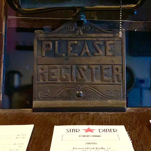 The old host stand with a bronze "please register" plaque