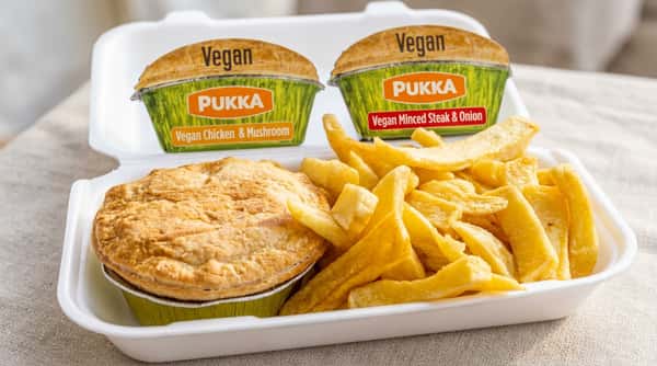 Pukka vegan pie and chips in a white takeaway container, with two other Pukka vegan pies in the background.