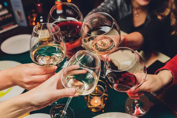 Group of friends toasting with glasses of red and white wine over a candlelit table at a festive gathering.