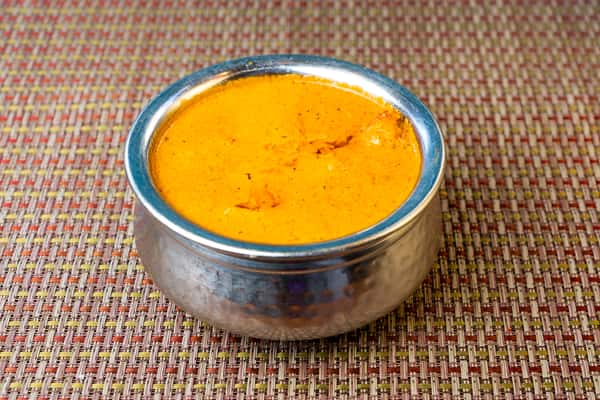 Creamy butter chicken in a rich tomato and cream sauce served in a traditional metal bowl — classic North Indian curry.
