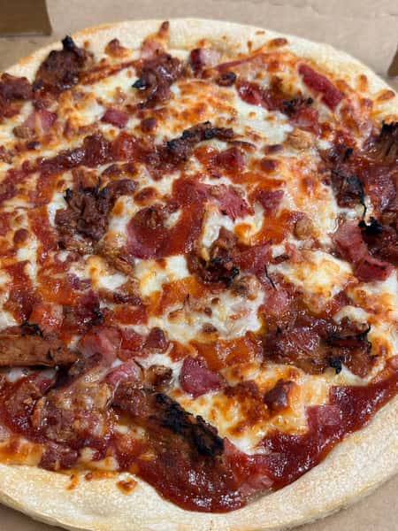 Meat lover's pizza from Elberta Pizza in Elberta, AL loaded with ham, bacon, and smoky pork toppings over mozzarella and tomato sauce.