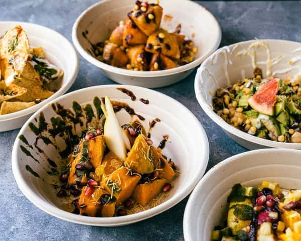 Modern Indian fusion small plates featuring roasted squash chaat with pomegranate seeds and chutneys, chickpea salad with fresh vegetables, grilled paneer bites, and creative vegetarian appetizers served in minimalist bowls on a contemporary restaurant table.