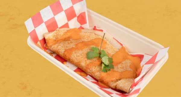 Crispy dosa topped with creamy orange chutney and fresh cilantro, served in a takeout tray, highlighting South Indian street food flavors.
