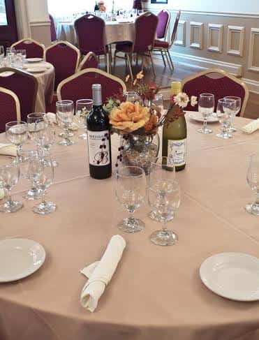 a table with a tablecloth and 8 chairs and place settings