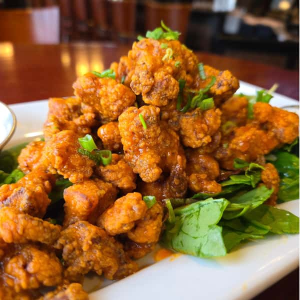 Crispy buffalo fried oysters tossed in spicy sauce, served over greens and topped with chopped scallions.