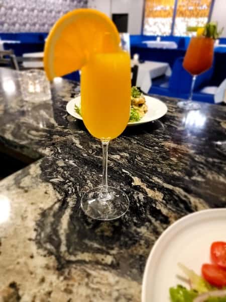 A refreshing glass of orange juice with a slice of orange, set against a marble countertop.