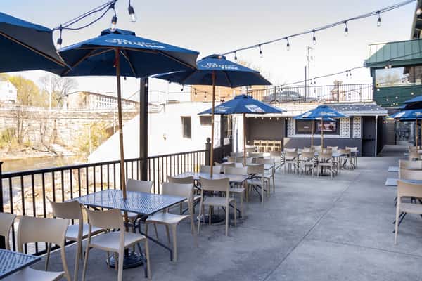 open-air patio seating with blue umbrellas and scenic riverside restaurant atmosphere