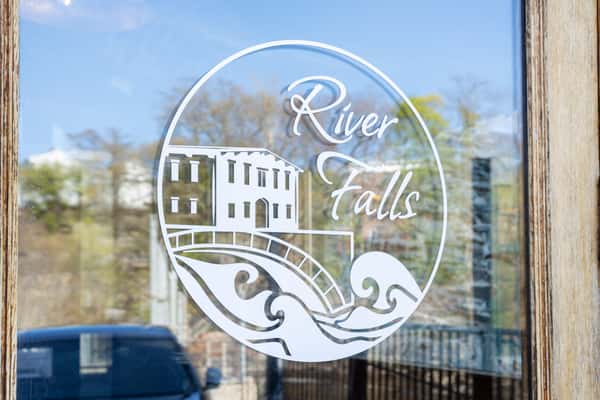restaurant window logo featuring River Falls branding with scenic outdoor reflections