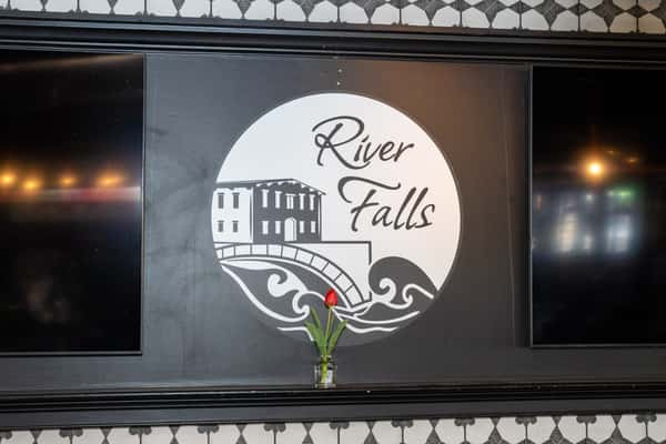 River Falls restaurant logo displayed on an interior wall with modern rustic decor