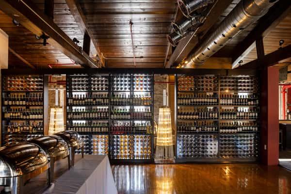 rustic restaurant interior with floor-to-ceiling wine shelves, warm wood accents, and upscale dining atmosphere