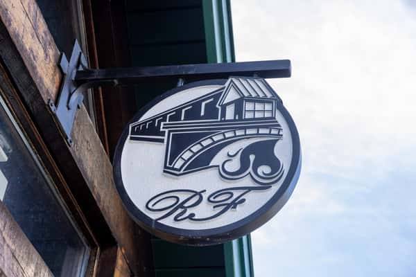 close-up of hanging restaurant signage with rustic branding and exterior architectural details